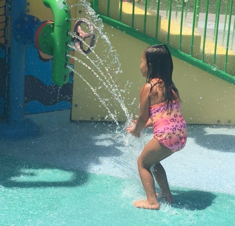 a girl playing in water from one of our children's department park days