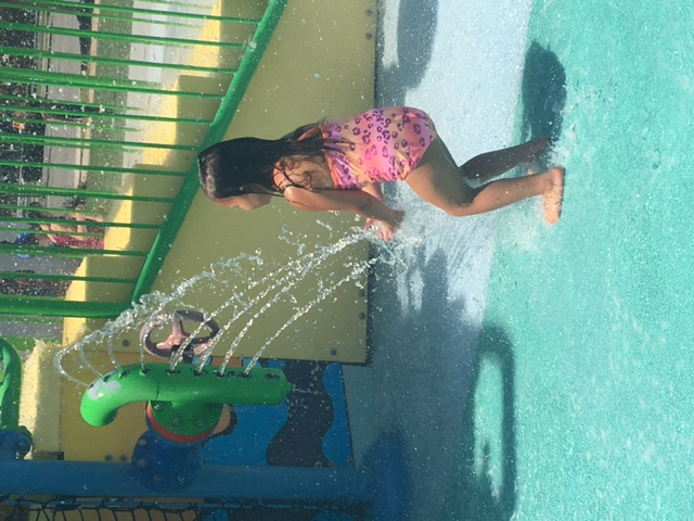 A little girl standing in water from a vertical sprinkler