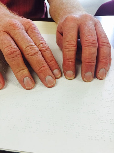Kelly reading Braille with two hands