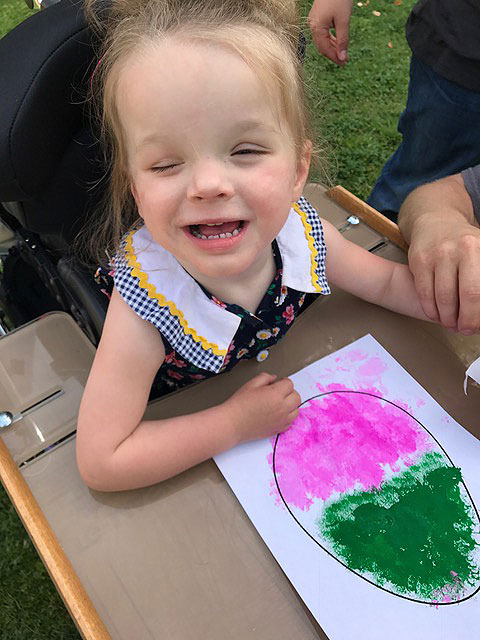 A child is smiling while coloring an Easter Egg