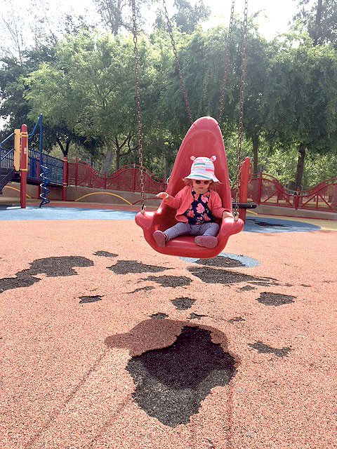 A child is sitting on a swing in the sensory playground at Fairmount Park