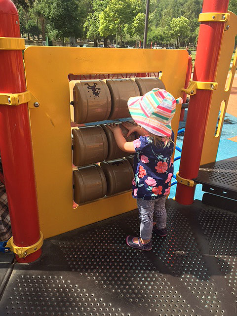 A little girl is playing with the sensory attractions on a wall