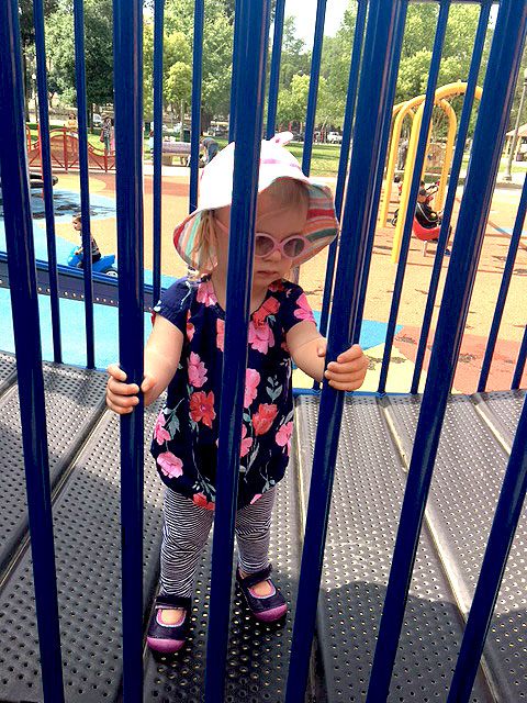 A child is behind the safety bars on a playplace at the sensory playground