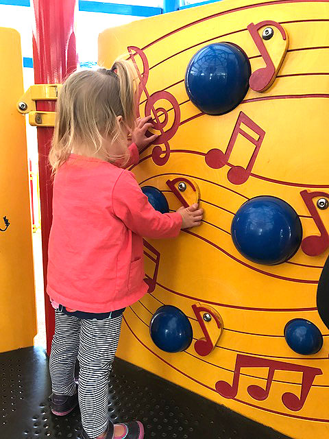 A little girl is playing at the audio sound wall