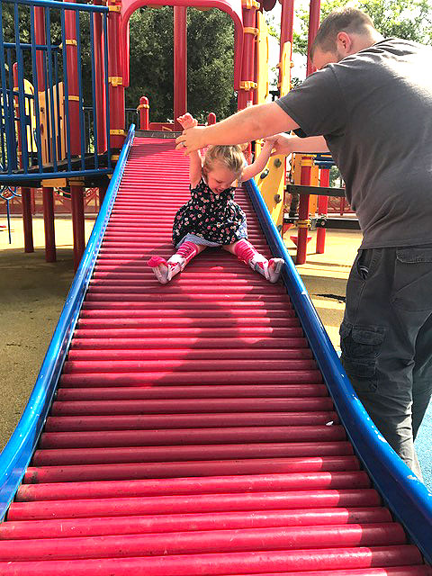 A father and his child are playing on the slide at Park Day
