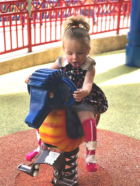 A child is playing on a rocking horse at the sensory playground