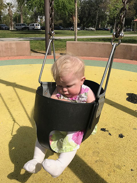 A baby is playing on a safety swing at the sensory playground